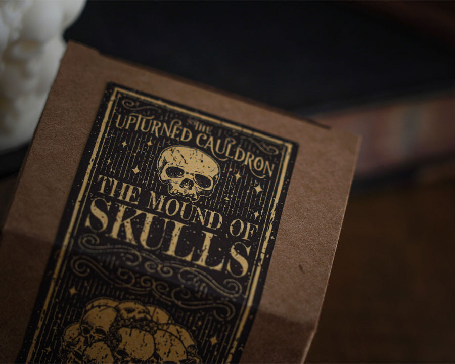 Candle in the shape of a pile of skulls box and label